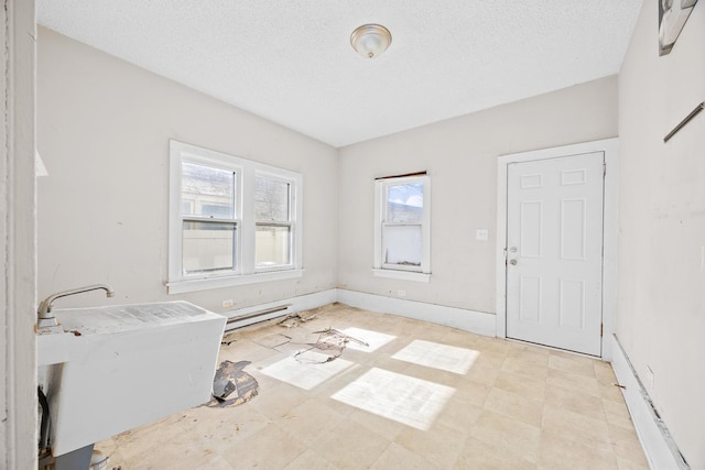 interior space with a textured ceiling, light floors, and baseboards