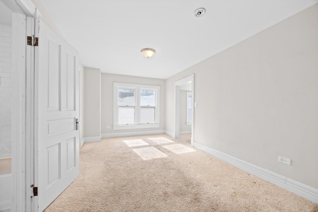 empty room featuring baseboards and light colored carpet