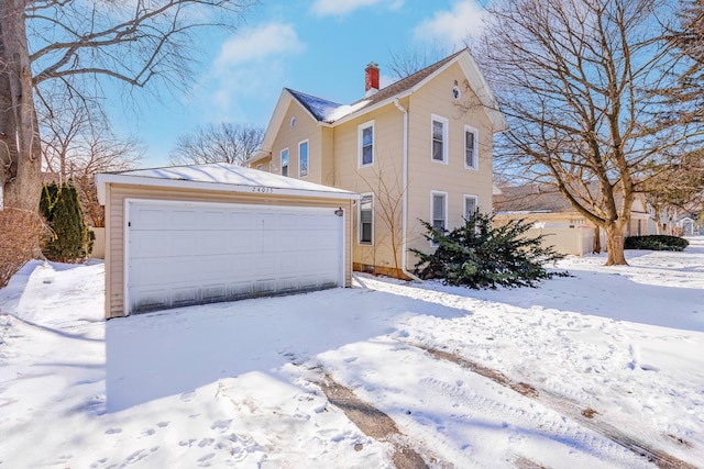 view of front of home featuring a detached garage, a chimney, and an outdoor structure