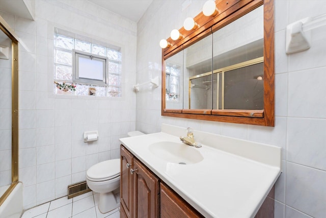 full bathroom with tile walls, vanity, toilet, tile patterned floors, and bath / shower combo with glass door