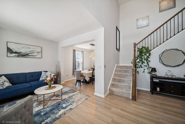 living room with an inviting chandelier, wood finished floors, baseboards, and stairs