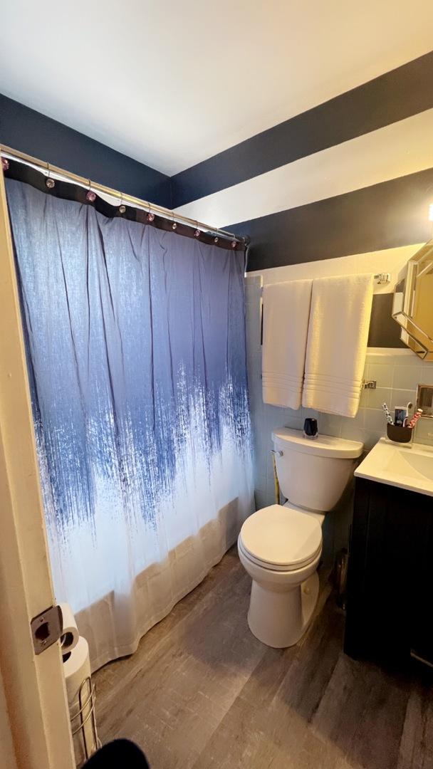 bathroom with toilet, walk in shower, backsplash, hardwood / wood-style floors, and vanity