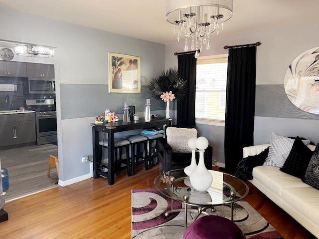 living room featuring sink, a notable chandelier, and light hardwood / wood-style flooring