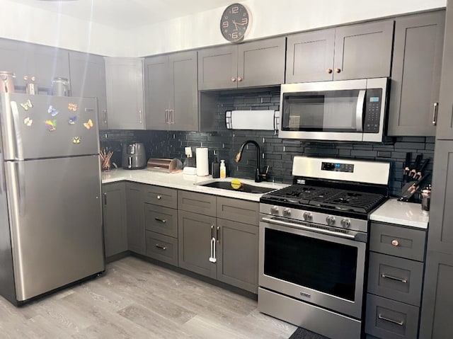 kitchen with sink, gray cabinets, tasteful backsplash, and stainless steel appliances