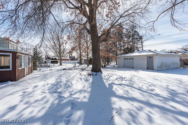 snowy yard featuring an outdoor structure and a garage