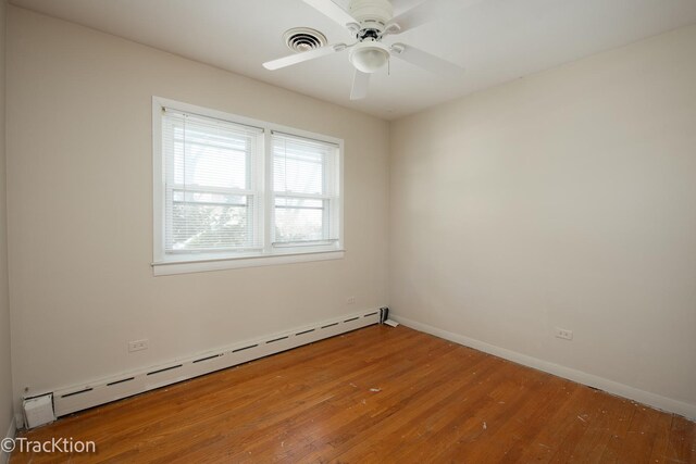 spare room featuring ceiling fan, baseboard heating, and wood-type flooring