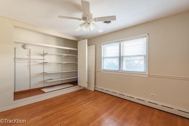 unfurnished bedroom featuring a baseboard radiator, ceiling fan, and wood-type flooring