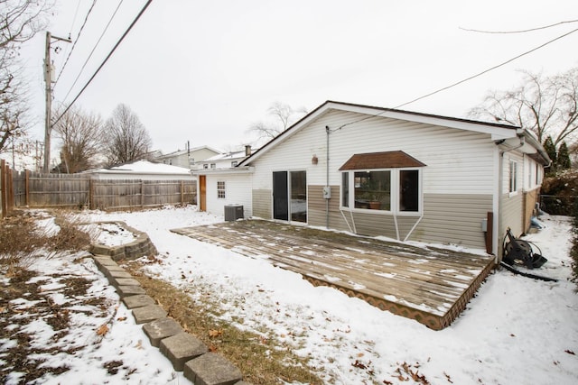 snow covered property featuring fence, a wooden deck, and cooling unit