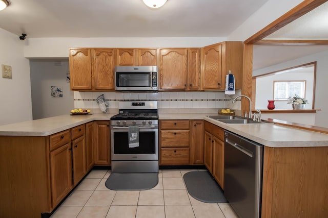 kitchen with decorative backsplash, a sink, light countertops, stainless steel appliances, and a peninsula