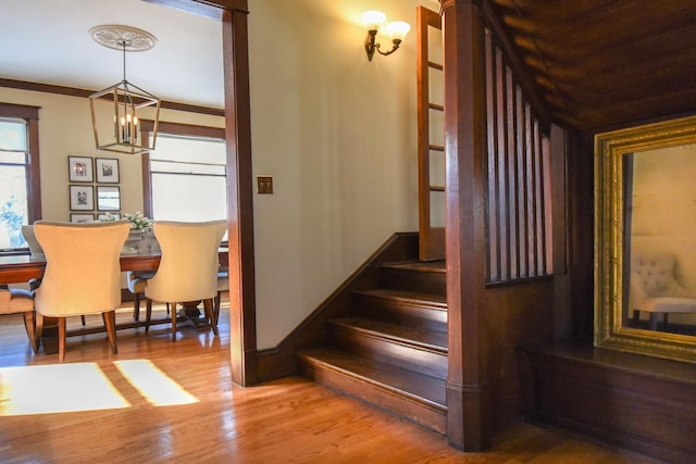 stairs featuring hardwood / wood-style floors, crown molding, and a notable chandelier