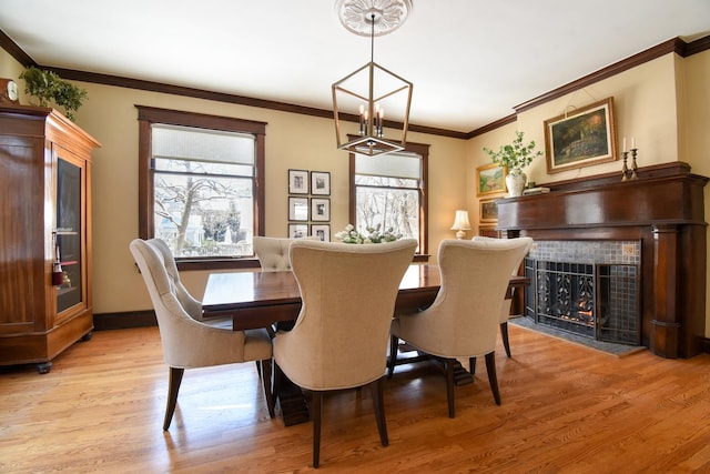 dining room with light wood-type flooring, a tiled fireplace, and plenty of natural light