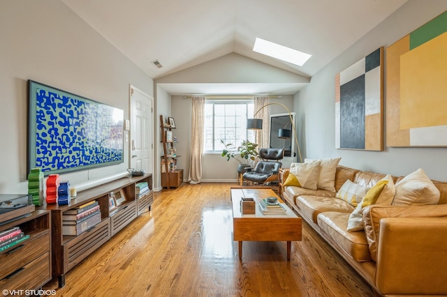 living room featuring lofted ceiling with skylight, light wood-type flooring, and visible vents