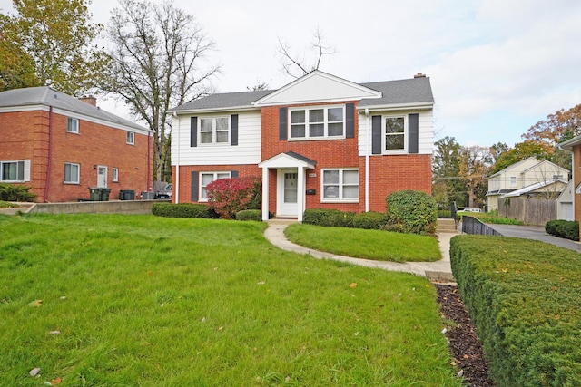 view of front facade with a chimney, fence, a front lawn, and brick siding