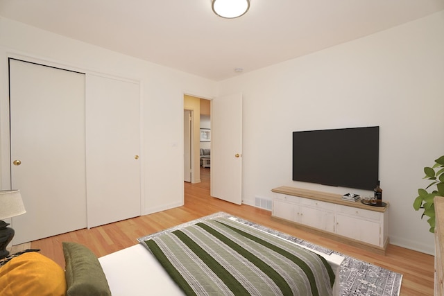 bedroom featuring baseboards, visible vents, and light wood finished floors