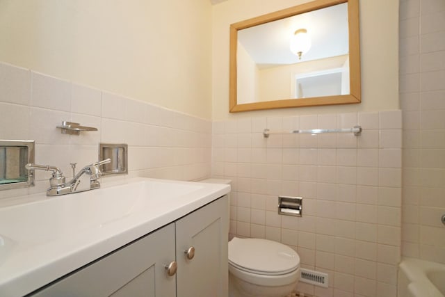 full bathroom with a wainscoted wall, tile walls, visible vents, toilet, and vanity