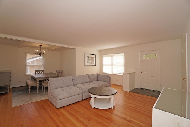 living area featuring light wood finished floors, baseboards, and a chandelier