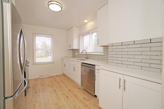 kitchen with stainless steel appliances, light countertops, visible vents, and white cabinetry