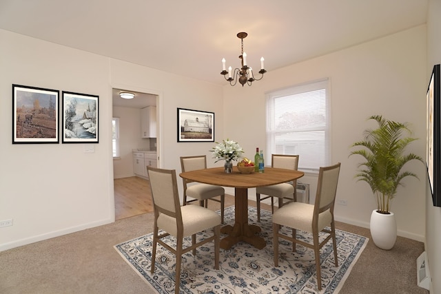 dining space with light carpet, baseboards, and a notable chandelier