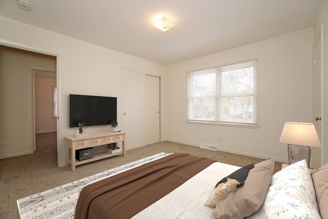 carpeted bedroom with baseboards, visible vents, and a closet