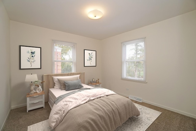 bedroom with baseboards, visible vents, and dark carpet