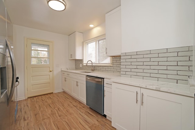 kitchen with white cabinetry, appliances with stainless steel finishes, light stone counters, and a sink