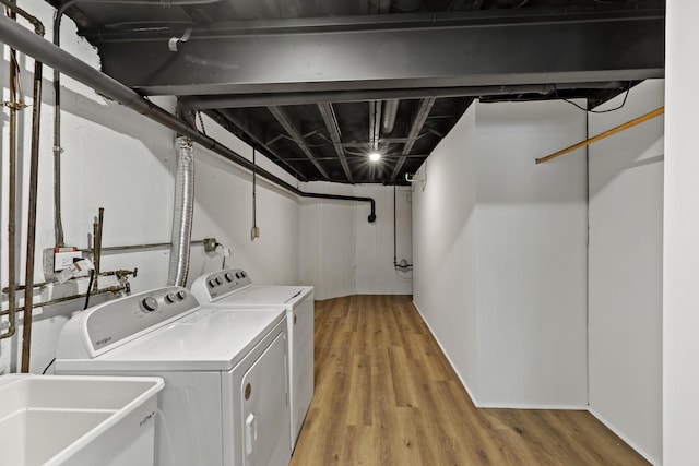 laundry area with wood-type flooring, washer and dryer, and sink