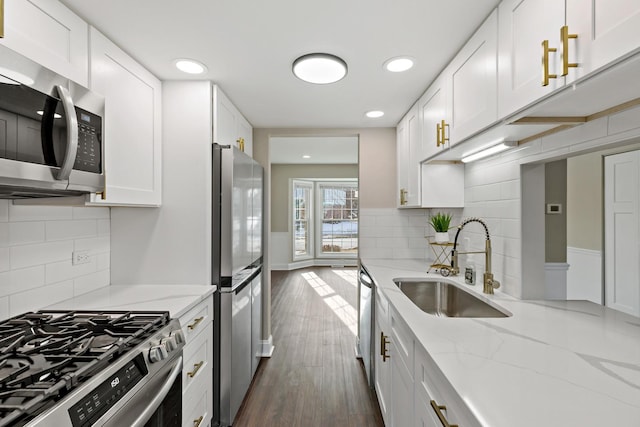 kitchen featuring sink, stainless steel appliances, white cabinetry, and light stone counters