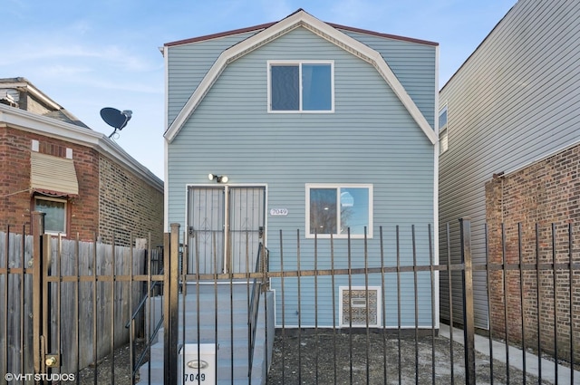 view of side of property with a gate, fence, and a gambrel roof