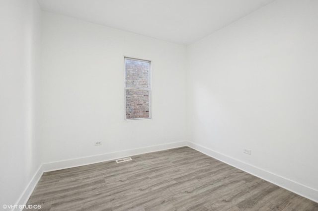 empty room featuring visible vents, baseboards, and wood finished floors