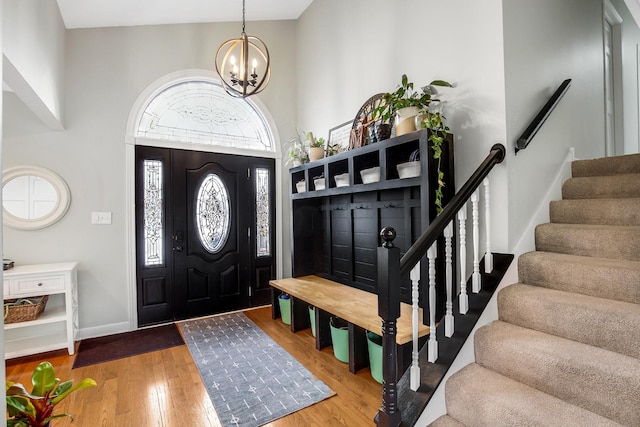 foyer with hardwood / wood-style flooring, a towering ceiling, and a notable chandelier