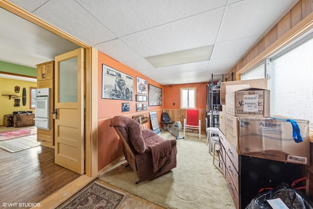 living area with light hardwood / wood-style floors and a paneled ceiling