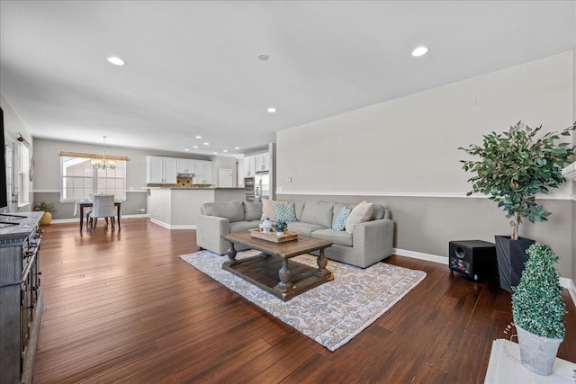 living room with an inviting chandelier and dark wood-type flooring