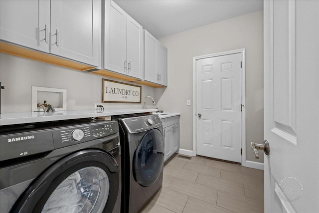 laundry room featuring washing machine and clothes dryer, sink, and cabinets