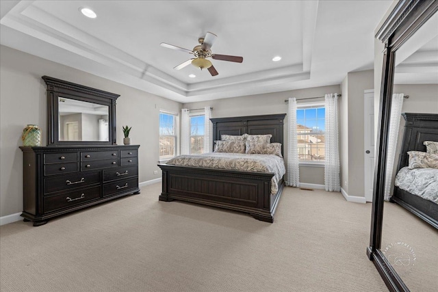 carpeted bedroom with a raised ceiling, multiple windows, and ceiling fan