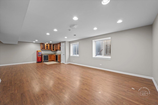 unfurnished living room with hardwood / wood-style floors, bar, and beverage cooler