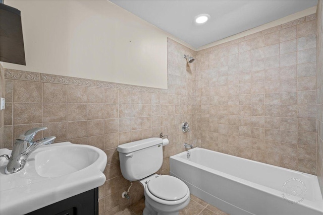 full bathroom with tiled shower / bath combo, toilet, tile walls, tile patterned floors, and vanity