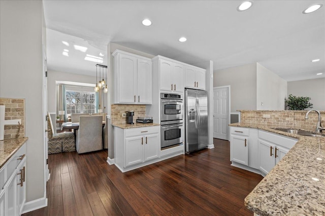 kitchen featuring sink, appliances with stainless steel finishes, white cabinetry, and pendant lighting