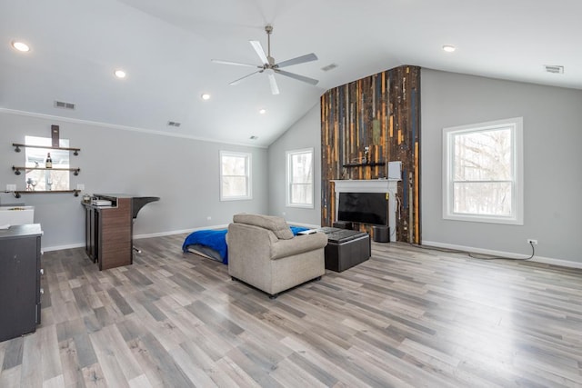 living room with a large fireplace, vaulted ceiling, wood finished floors, and visible vents