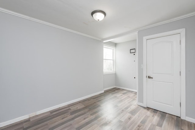 unfurnished room featuring light wood-style flooring, baseboards, and crown molding