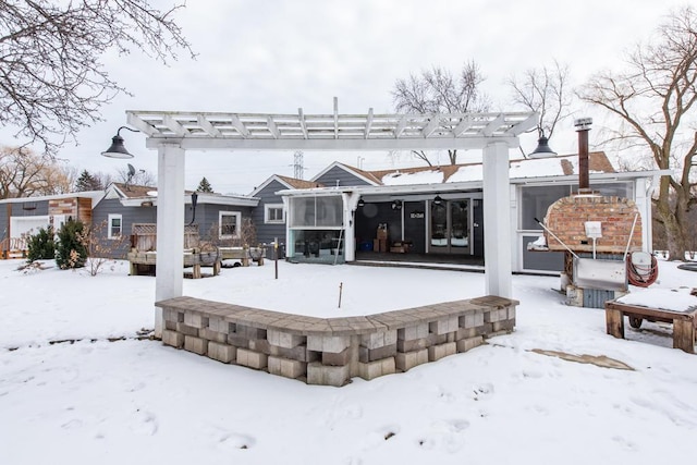 snow covered back of property featuring a pergola