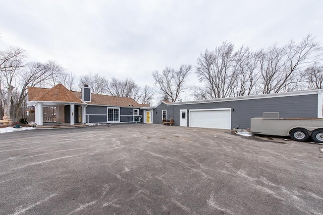 view of front of home with a garage, a chimney, and aphalt driveway