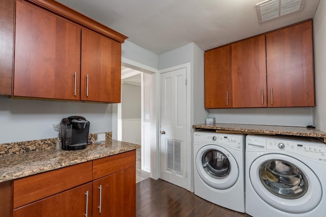 clothes washing area with washer and dryer, dark wood-style flooring, visible vents, and cabinet space