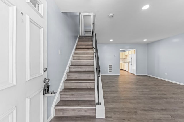 staircase with baseboards, wood finished floors, visible vents, and recessed lighting