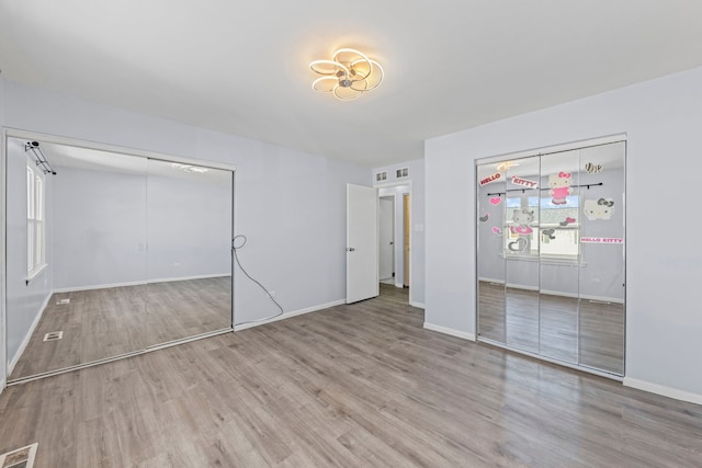 unfurnished bedroom with light wood finished floors, visible vents, and baseboards