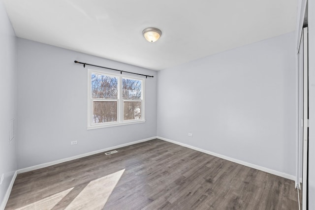 empty room featuring baseboards, visible vents, and wood finished floors