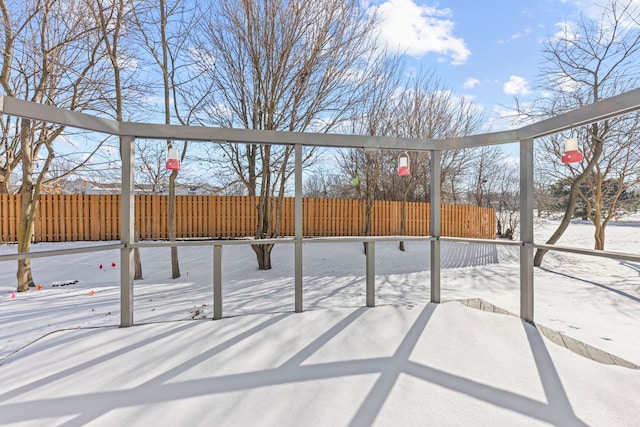 yard covered in snow featuring basketball hoop and fence