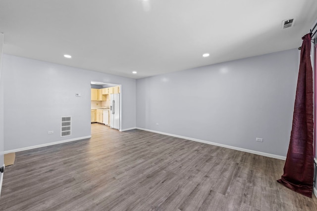 spare room featuring wood finished floors, visible vents, and baseboards