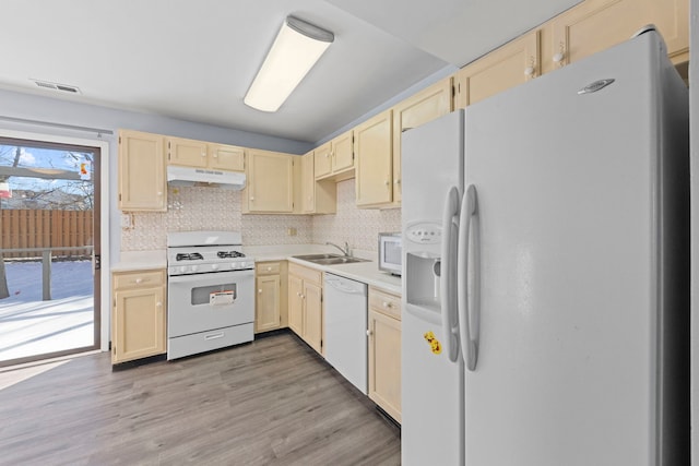 kitchen with under cabinet range hood, white appliances, a sink, light countertops, and light wood-type flooring