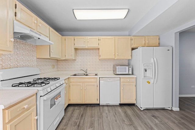 kitchen with white appliances, tasteful backsplash, light countertops, under cabinet range hood, and a sink