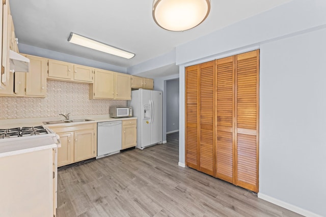 kitchen with tasteful backsplash, light wood-type flooring, white appliances, and light countertops